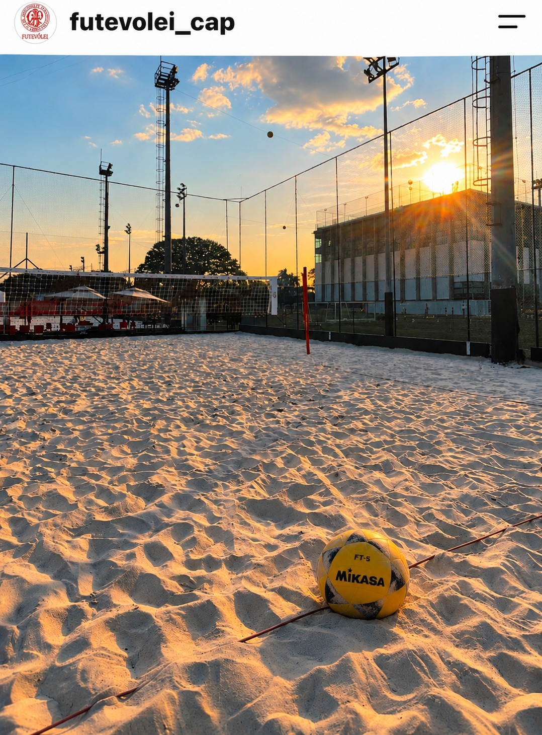 Quadra de futevôlei do Paulistano ao pôr do sol, com uma bola sobre a areia